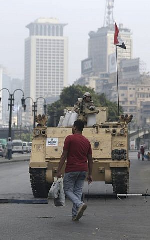 An Egyptian walks in front of an army armored vehicle that guards an entrance of Tahrir Square, in Cairo, Egypt, Friday, August 16, 2013. (photo credit: AP Photo/Hassan Ammar)