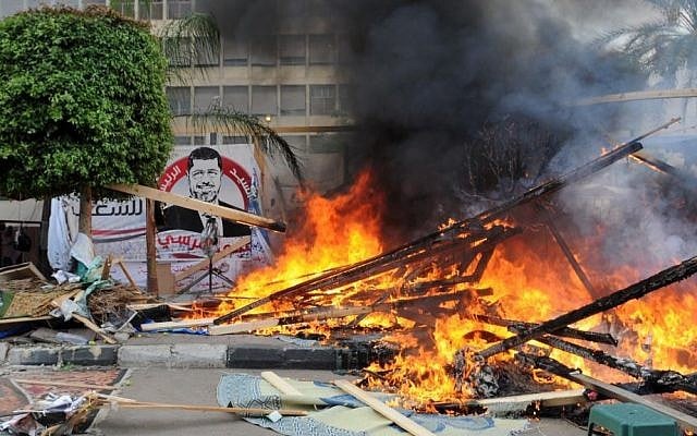 Makeshift wooden huts burn at a sit-in camp set up by supporters of ousted Islamist President Mohammed Morsi as Egyptian security forces clear the camp near Cairo University in Cairo's Giza district, Egypt, on Wednesday, Aug. 14, 2013. (photo credit: AP Photo/Mohammed Asad)