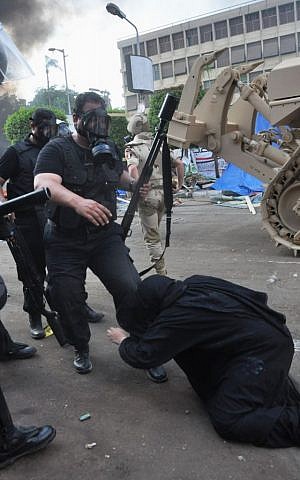 An Egyptian security force confronts a woman at a sit-in camp set up by supporters of ousted Islamist President Mohammed Morsi near Cairo University in Cairo's Giza district, Egypt, Wednesday, August 14, 2013. (photo credit: AP Photo/Hussein Tallal)