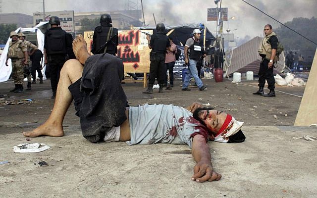 A wounded protester lies on the ground as Egyptian security forces clear the smaller of the two sit-ins by supporters of ousted Islamist President Mohammed Morsi, near the Cairo University campus in Giza, Cairo, Egypt, Wednesday, Aug. 14, 2013. (Photo credit: AP/Imad Abdul Rahman)