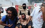 Supporters of ousted Islamist president Mohammed Morsi carry an injured protester at a sit-in camp in Cairo, August 14, 2013. (photo credit: AP/Mohammed Asad)