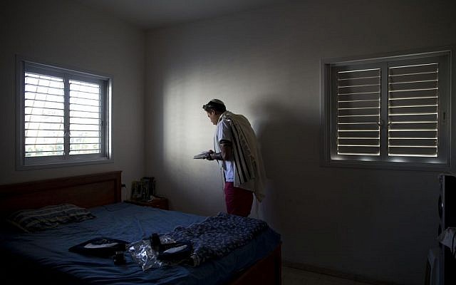 Israeli Orthodox Jew Shahar Hadar, also a drag queen, is seem covered by a prayer shawl during a morning prayer session, July 31, 2013, (photo credit:AP/Oded Balilty)