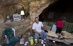 Palestinian Khaled Zir sits with his children inside a cave in the east Jerusalem neighborhood of Silwan, Tuesday, Aug. 27, 2013. Zir said the family moved into a cave after their home was demolished by Israeli authorities. (photo credit: AP/Sebastian Scheiner)