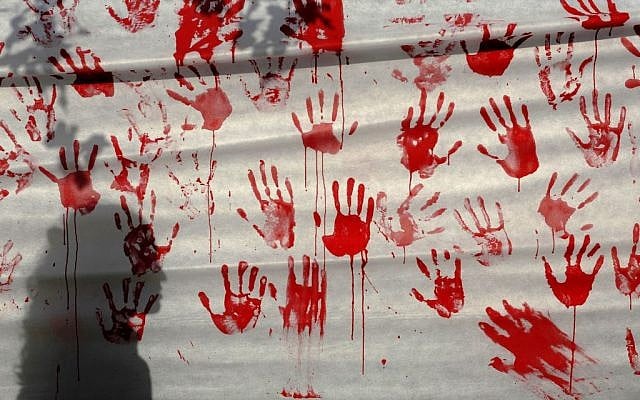A person stands next to a banner with hand stamps in red paint during a protest in Tel Aviv against the prisoner release Monday. Many of the prisoners to be released are said to "have blood on their hands." (photo credit: AP/Tsafrir Abayov) A person stands next to a banner with hand stamps in red paint during a protest in Tel Aviv against the prisoner release Monday. Many of the prisoners to be released are said to "have blood on their hands." (photo credit: AP/Tsafrir Abayov)