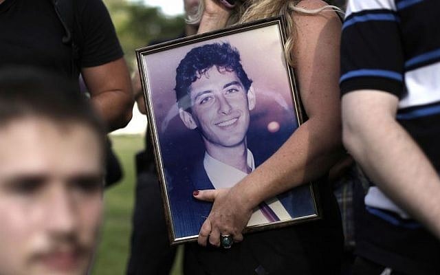 An Israeli holds a portrait of a relative killed in a terror attack during a protest in Tel Aviv on Monday as people protested the government's decision to release 26 Palestinian prisoners, most of them held for deadly attacks, as part of a US-brokered deal that led to a resumption of Mideast negotiations. (photo credit: AP Photo/Tsafrir Abayov)