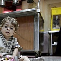 A Syrian woman who fled her home because of Syria’s civil war prepares a meal in the kitchen as her child looks at the camera at the Kertaj Hotel in Damascus, Syria. (Photo credit: AP/Hassan Ammar) A Syrian woman who fled her home because of Syria’s civil war prepares a meal in the kitchen as her child looks at the camera at the Kertaj Hotel in Damascus, Syria. (Photo credit: AP/Hassan Ammar)