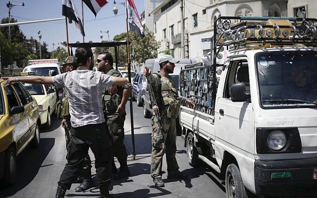 Syrian military soldiers check identifications and search vehicles at a check point on Baghdad street, in Damascus, on Wednesday, August 21, 2013. (photo credit: AP/Hassan Ammar) Syrian military soldiers check identifications and search vehicles at a check point on Baghdad street, in Damascus, on Wednesday, August 21, 2013. (photo credit: AP/Hassan Ammar)