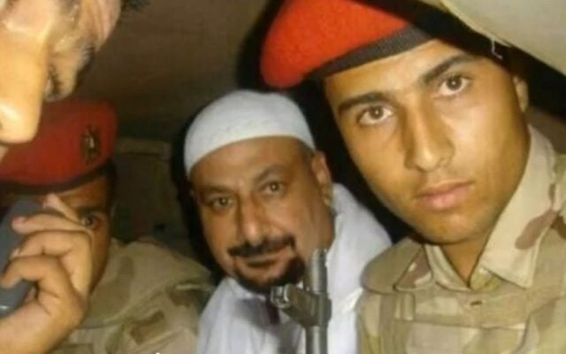 Safwat Hegazy, in white, with soldiers after being captured, in a photo which aired on Egyptian State TV. (Screenshot: YouTube) Safwat Hegazy, in white, with soldiers after being captured, in a photo which aired on Egyptian State TV. (Screenshot: YouTube)