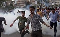 Supporters of Egypt's ousted president Mohammed Morsi run for cover from tear gas fired by police (not seen), during a protest in Cairo, Egypt, on August 30, 2013 (photo credit: AP/Khalil Hamra)