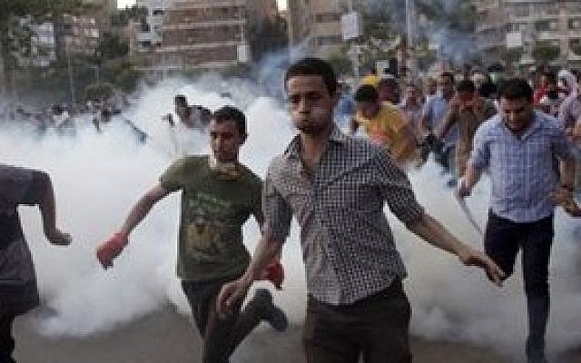 Supporters of Egypt's ousted president Mohammed Morsi run for cover from tear gas fired by police (not seen), during a protest in Cairo, Egypt, on August 30, 2013 (photo credit: AP/Khalil Hamra)