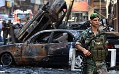 A Lebanese soldier passes in front of burned cars at the site of a car bombing in southern Beirut, on August 16, 2013 (photo credit: AP/Hussein Malla/File)