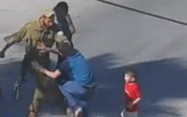 A soldier seen kicking a Palestinian boy in Hebron (photo credit: YouTube screen cap)