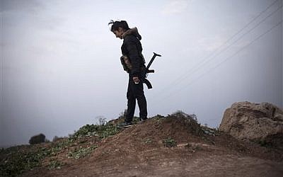 A Kurdish female member of the Popular Protection Units stands guard at a checkpoint near the northeastern city of Qamishli, Syria, March 3, 2013. (photo credit: AP/Manu Brabo)