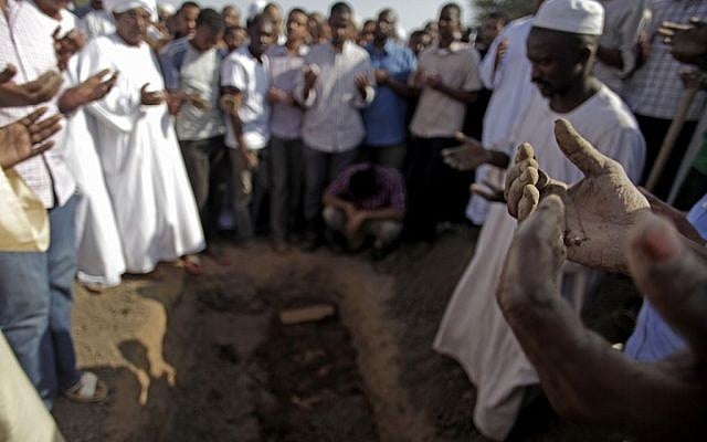 Sudanese men pray over the body of Salah Sanhory, 26, who was killed on Friday Sept. 27, 2013 by security forces, during his funeral in Khartoum, Sudan, Saturday, Sept. 28, 2013. (photo credit: AP/Khalil Hamra) Sudanese men pray over the body of Salah Sanhory, 26, who was killed on Friday Sept. 27, 2013 by security forces, during his funeral in Khartoum, Sudan, Saturday, Sept. 28, 2013. (photo credit: AP/Khalil Hamra)