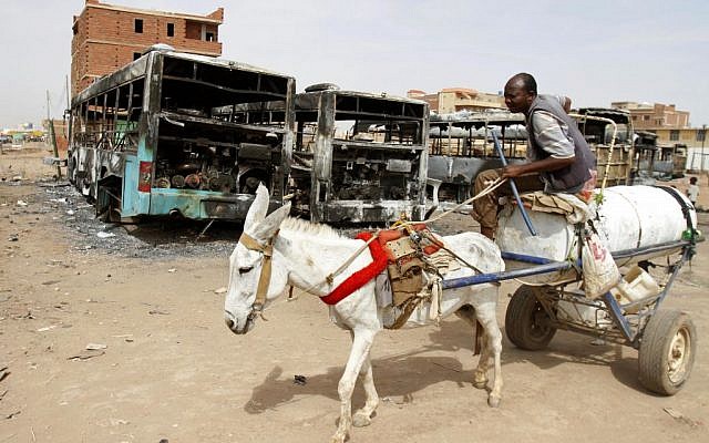 A man on a donkey cart passes burned buses following rioting and unrest in Khartoum, Sudan, Thursday, September 26, 2013. Sudanese authorities have deployed troops around vital installations and gas stations in Khartoum following days of deadly rioting over gas price hikes. (photo credit: AP Photo/Abd Raouf) A man on a donkey cart passes burned buses following rioting and unrest in Khartoum, Sudan, Thursday, September 26, 2013. Sudanese authorities have deployed troops around vital installations and gas stations in Khartoum following days of deadly rioting over gas price hikes. (photo credit: AP Photo/Abd Raouf)