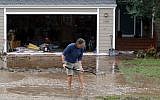 A man clears a drains in front of a house in Boulder, Colorado, on Thursday (photo credit: AP/Ed Andrieski)