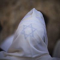 A religious Jew of the priestly caste spreads his prayer shawl over his head as he takes part in the priestly blessing during the Jewish holiday of Sukkot, Sunday, September 22, 2013 (photo credit: Yonatan Sindel/Flash90)