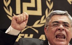In this May 6, 2012 file photo, Golden Dawn party leader Nikos Michaloliakos speaks during a news conference in front of a banner with the twisting Maeander, an ancient Greek decorative motif that the party has adopted as its symbol, in Athens. (AP/Petros Giannakourism, File)
