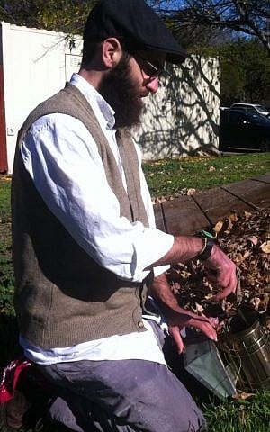 Beekeeper Uri Laio mixes up a smoking brew to tame his buzzing friends. (photo credit: Chavie Lieber/Times of Israel)