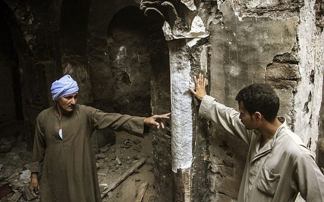 Egyptian Christian villagers point out a damaged column that they claim drips water every Good Friday at the damaged ancient chapel inside the Virgin Mary and St. Abraam Monastery that was looted and burned by Islamists in Dalga, Minya province, Egypt. (AP Photo/El Shorouk Newspaper, Roger Anis)
