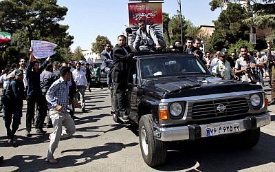 A protester, left, approaches President Hasan Rouhani's car leaving Mehrabad airport after his arrival from the U.S. in Tehran, Iran, Saturday, Sept. 28, 2013.(photo credit: AP Photo/Ebrahim Noroozi)