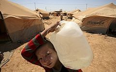 A Syrian boy carries a water jug to his family's tent at the Zaatari Refugee Camp, in Mafraq, Jordan (photo credit: AP/Mohammad Hannon/File)