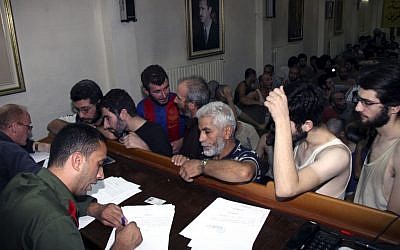 In this file photo, Syrian prisoners sign their papers of release at the Damascus Police Command headquarters in Damascus, Syria, on September 1, 2012. (photo credit: AP/Bassem Tellawi)