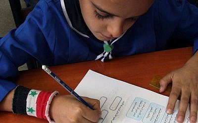 In this Wednesday, Sept. 18, 2013 photo, a Syrian boy writes in his workbook during a lesson at Hassan Shuaib School in Damascus, Syria. (AP Photo)