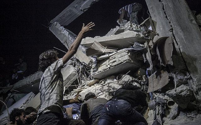 In this Sunday, September 22, 2013 photo, Syrian villagers remove debris as they try to rescue victims, not pictured, of a building destroyed due to an airstrike that hit a village turned into a battlefield between government forces and Free Syrian Army fighters in Idlib province, northern Syria. (photo credit: AP Photo)