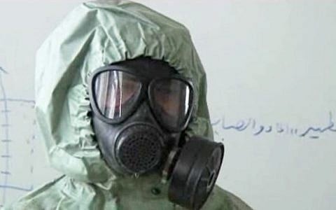 This image made from a video posted on September 18, 2013, shows a student wearing a gas mask and protective suit during a classroom session on how to respond to a chemical weapons attack in Aleppo, Syria. (photo credit: AP)