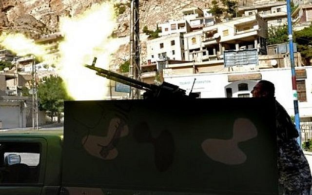 A Syrian army soldier fires a heavy machine gun during clashes with rebels in the village of Maaloula, northeast of Damascus, Syria, on Saturday, September 7, 2013. (photo credit: AP/SANA) A Syrian army soldier fires a heavy machine gun during clashes with rebels in the village of Maaloula, northeast of Damascus, Syria, on Saturday, September 7, 2013. (photo credit: AP/SANA)