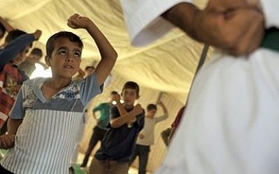 Syrian refugee children look at their Korean Taekwondo instructor at Zaatari refugee camp near Mafraq, Jordan, Tuesday, Sept. 17, 2013 (photo credit: AP/Bela Szandelszky)