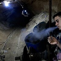 A Palestinian smokes in one of Gaza's smuggling tunnels (photo credit: Hatem Moussa/AP) A Palestinian smokes in one of Gaza's smuggling tunnels (photo credit: Hatem Moussa/AP)