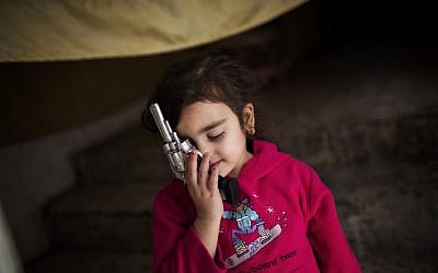 A Syrian refugee girl plays with a toy gun at her family's house in Zarqa, Jordan's industrial center, where thousands of Syrian refugees are living, northeast of the capital Amman. More than 420,000 Syrian refugees have settled in Jordan's cities, struggling for survival on UN foods stamps and straining the meager resources of a country that absorbed millions of exiles from the region's hotspots in the past. (AP Photo/Manu Brabo)