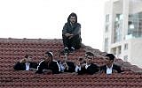 Mourners atop a Jerusalem roof on Monday evening watch the funeral procession for Rabbi Ovadia Yosef, who died on Monday afternoon. (photo credit: Nati Shohat/Flash90)