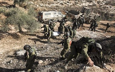 IDF soldiers carry away the body of armed Palestinian terror suspect Mohamed Aazi near the West Bank village of Bil'in, near Ramallah October 22, 2013.  (Photo credit: Issam Rimawi /FLASH90)