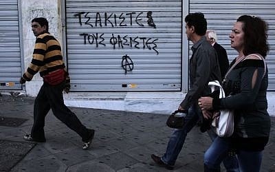 Pedestrians walk past graffiti that reads 'crush the fascists' in Athens' Syntagma square on Friday Oct. 11, 2013. Anti-fascist messages in public spaces around Athens increased after lawmakers and members of the extreme right party Golden Dawn were jailed. (photo credit: AP Photo/Dimitri Messinis)