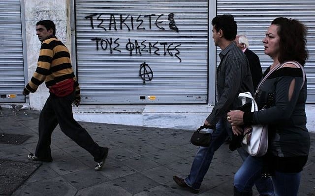 Pedestrians walk past graffiti that reads 'crush the fascists' in Athens' Syntagma square on Friday Oct. 11, 2013. Anti-fascist messages in public spaces around Athens increased after lawmakers and members of the extreme right party Golden Dawn were jailed. (photo credit: AP Photo/Dimitri Messinis) Pedestrians walk past graffiti that reads 'crush the fascists' in Athens' Syntagma square on Friday Oct. 11, 2013. Anti-fascist messages in public spaces around Athens increased after lawmakers and members of the extreme right party Golden Dawn were jailed. (photo credit: AP Photo/Dimitri Messinis)