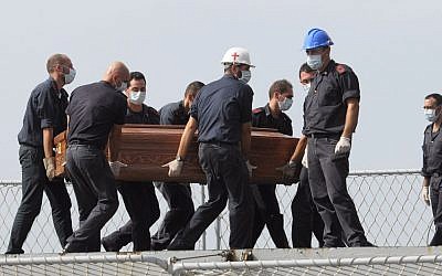 The casket of one of the migrants who died when their boat capsized off in the Canal of Sicily is carried aboard a Italian Navy ship at the Lampedusa island harbor, Saturday, Oct. 12, 2013 (photo credit: AP/Amedeo Fragapane)