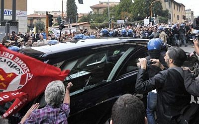 A woman holding a flag of Italian Communist Refoundation Party thumps her fist on the hearse carrying the coffin of Nazi war criminal Erich Priebke as it arrives at the Society of St. Pius X, a schismatic Catholic group, in Albano Laziale, on the outskirts of Rome, Tuesday, Oct. 15, 2013. (photo credit: AP Photo/Lapresse)