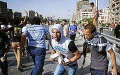 A supporter of Egypt's ousted president Mohammed Morsi holds bricks during clashes on the Al-Malek Al-Saleh bridge in Cairo, Egypt, on Friday (photo credit: AP/Hamada Elrasam)