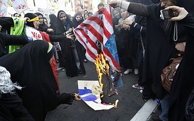 Iranian female demonstrators burn a representation of the US flag and a caricature of President Barack Obama in an annual state-backed rally in front of the former US Embassy in Tehran, Iran, in November 2012. (photo credit: AP/Vahid Salemi/File)