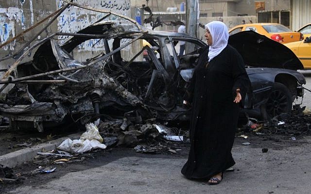 A woman inspects the site of a deadly car bomb attack that killed her sister, in Baghdad, Iraq, October 2013 (photo credit: AP/Hadi Mizban) A woman inspects the site of a deadly car bomb attack that killed her sister, in Baghdad, Iraq, October 2013 (photo credit: AP/Hadi Mizban)