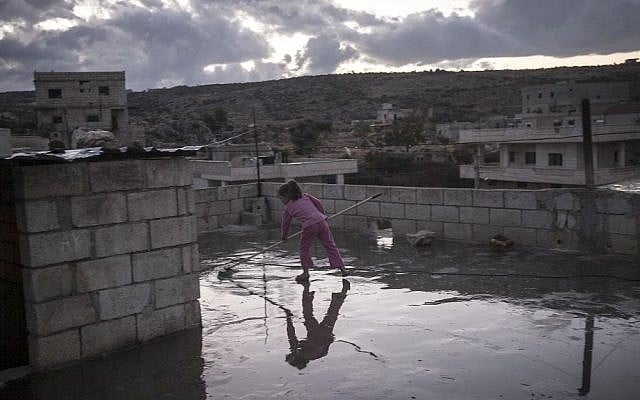 Clearing water from a rooftop in Kfat Lata, Syria, on Thursday, October 3, 2013. (photo credit: AP Photo) 