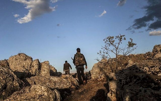 Opposition fighters, sons of Mohammed Kale, walk on the outskirts of Kfar Lata. (photo credit: AP Photo)