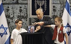 President Shimon Peres lights a candle near a picture of late Israeli Prime Minister Yitzhak Rabin, at a memorial ceremony to commemorate the 18th anniversary of Rabin's assassination,  in Jerusalem, October 15, 2013 (photo credit: Miriam Alster/Flash90)
