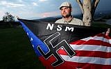 In this Oct. 22, 2010 file photo, Jeff Hall, who was killed by his son, holds a Neo Nazi flag while standing at Sycamore Highlands Park near his home in Riverside, Calif. (photo credit: AP Photo/Sandy Huffaker, File)