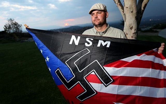 In this Oct. 22, 2010 file photo, Jeff Hall, who was killed by his son, holds a Neo Nazi flag while standing at Sycamore Highlands Park near his home in Riverside, Calif. (photo credit: AP Photo/Sandy Huffaker, File) In this Oct. 22, 2010 file photo, Jeff Hall, who was killed by his son, holds a Neo Nazi flag while standing at Sycamore Highlands Park near his home in Riverside, Calif. (photo credit: AP Photo/Sandy Huffaker, File)
