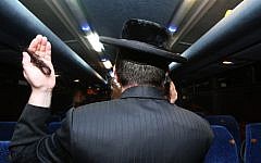 A man on a bus near Beitar Illit holds up one of his sidelocks that had been cut off by a knife-wielding Palestinian, October 20, 2013. (photo credit: Nati Shohat/Flash90)