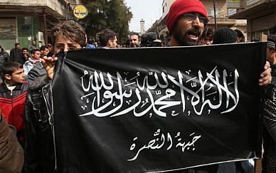 Anti-Syrian President Bashar Assad protesters hold the Jabhat al-Nusra flag, as they shout slogans during a demonstration, at Kafranbel town, in Idlib province, northern Syria March 1, 2013. Leader of al-Qaeda in Syria Abu Mohammad al-Golani heads the al-Nusra Front rebel faction. (photo credit: (AP Photo/Hussein Malla, File)